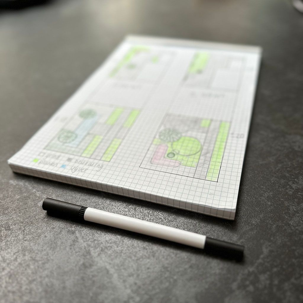 Een tuinontwerp getekend op ruitjespapier, met een stift ernaast